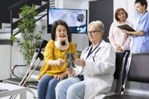 Doctor examining woman patient with neck fracture during routine appointment in modern clinic lobby. Medic offers includes recommendations for physiotherapy and appropriate painkillers.